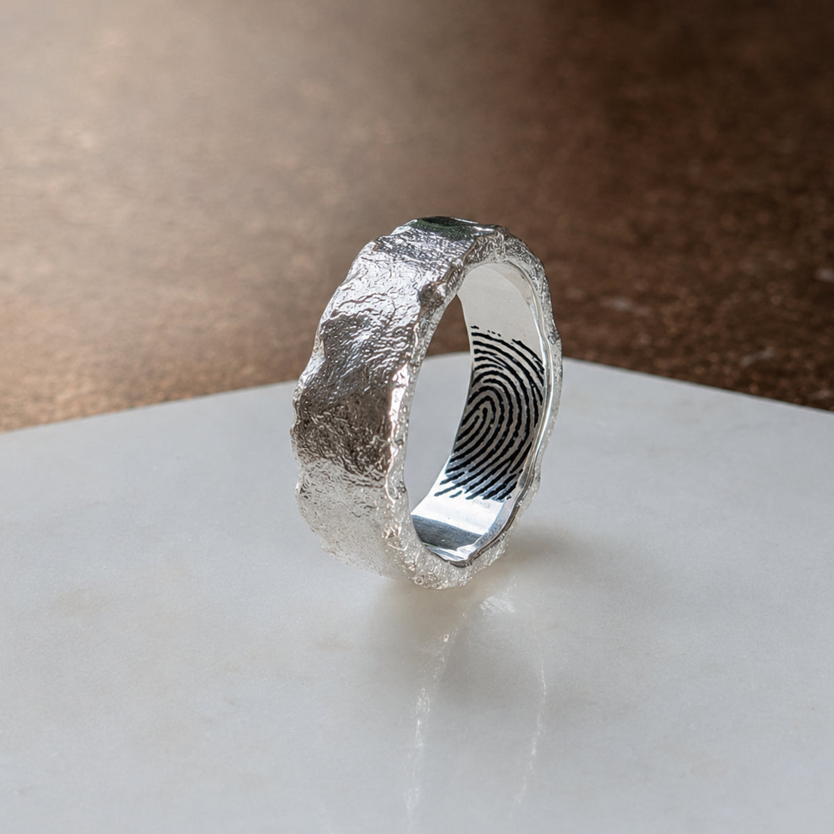 Handmade molten sterling silver fingerprint ring with a rugged organic texture, featuring a personalised fingerprint engraved inside the wide band.