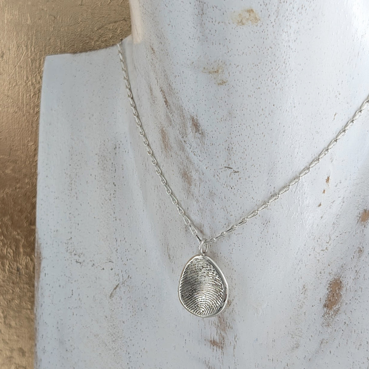 Organic shaped molten metal fingerprint necklace on silver chain