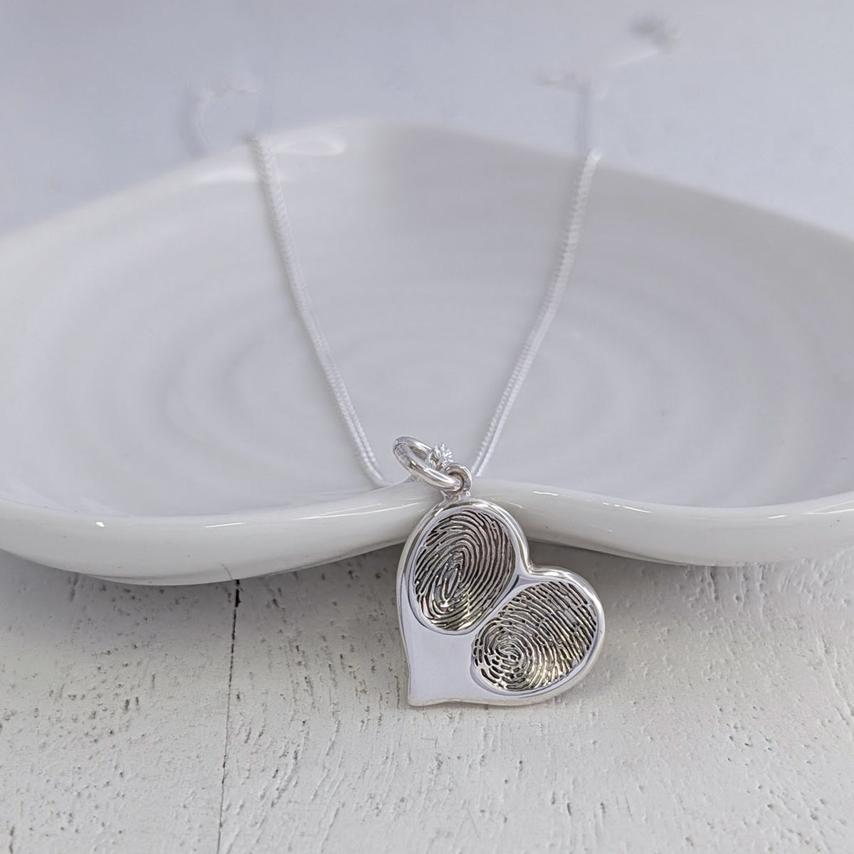 Personalised double fingerprint heart necklace handcrafted in sterling silver, featuring two real fingerprints engraved within a contemporary heart pendant keepsake.