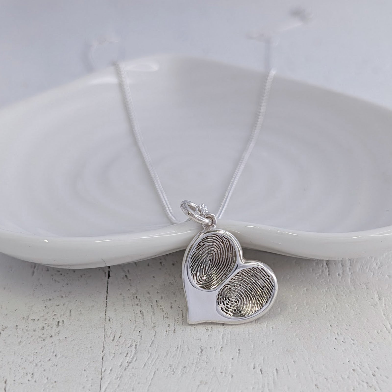 Personalised double fingerprint heart necklace handcrafted in sterling silver, featuring two real fingerprints engraved within a contemporary heart pendant keepsake.