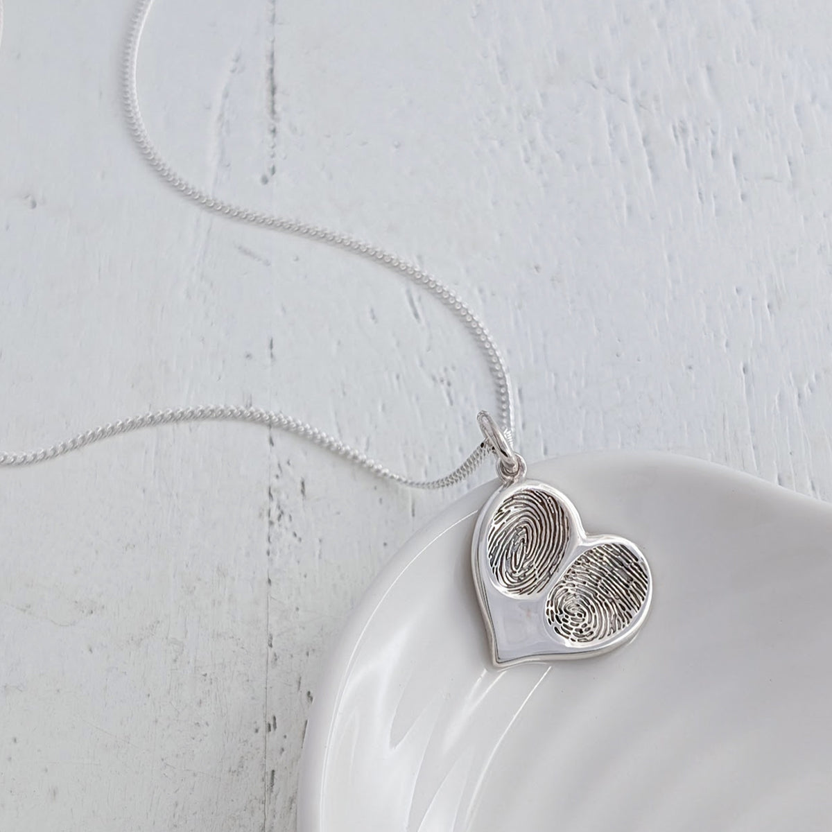 Bespoke silver fingerprint heart pendant necklace, custom made with two loved ones’ fingerprints to create a meaningful memorial or family jewellery gift.