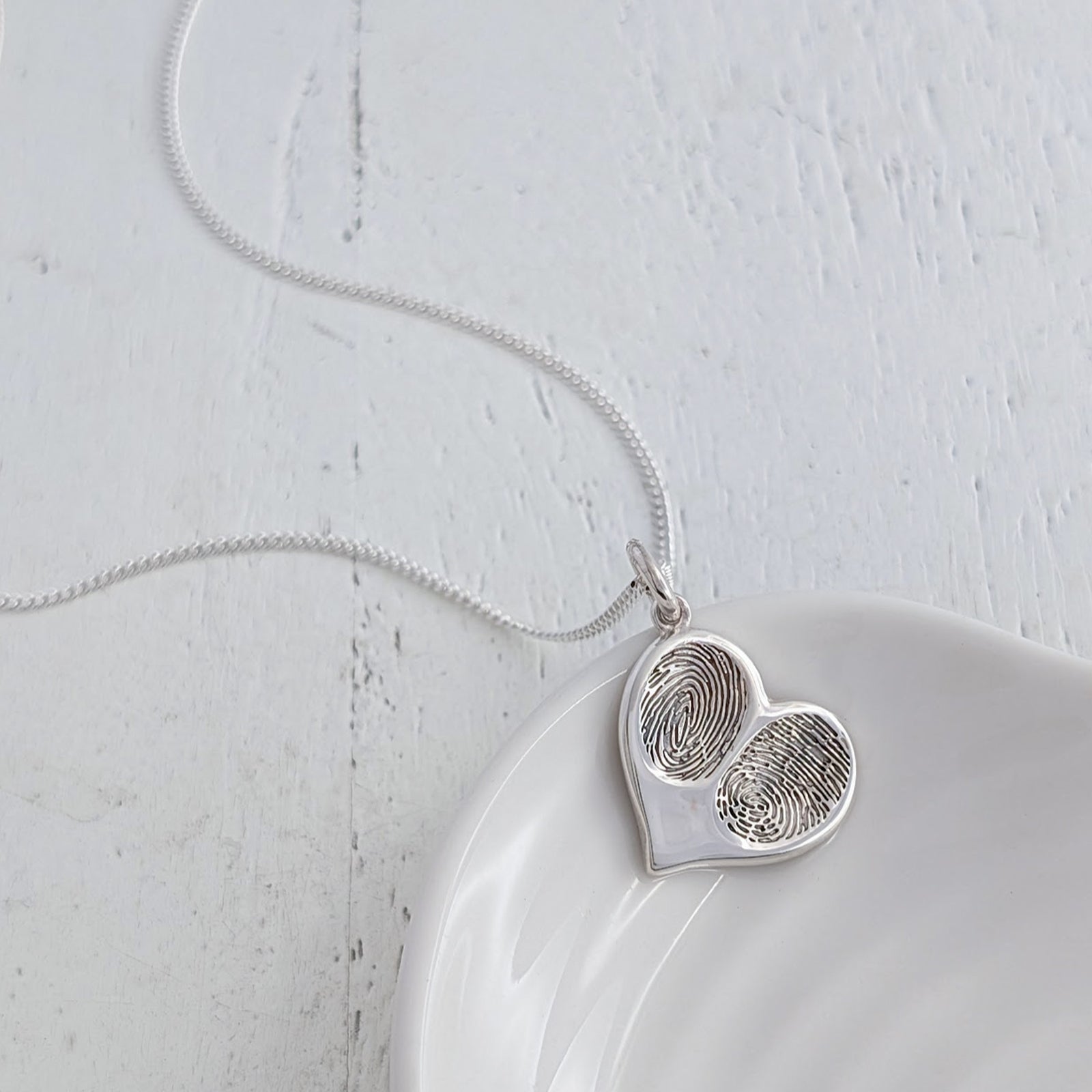 Bespoke silver fingerprint heart pendant necklace, custom made with two loved ones’ fingerprints to create a meaningful memorial or family jewellery gift.