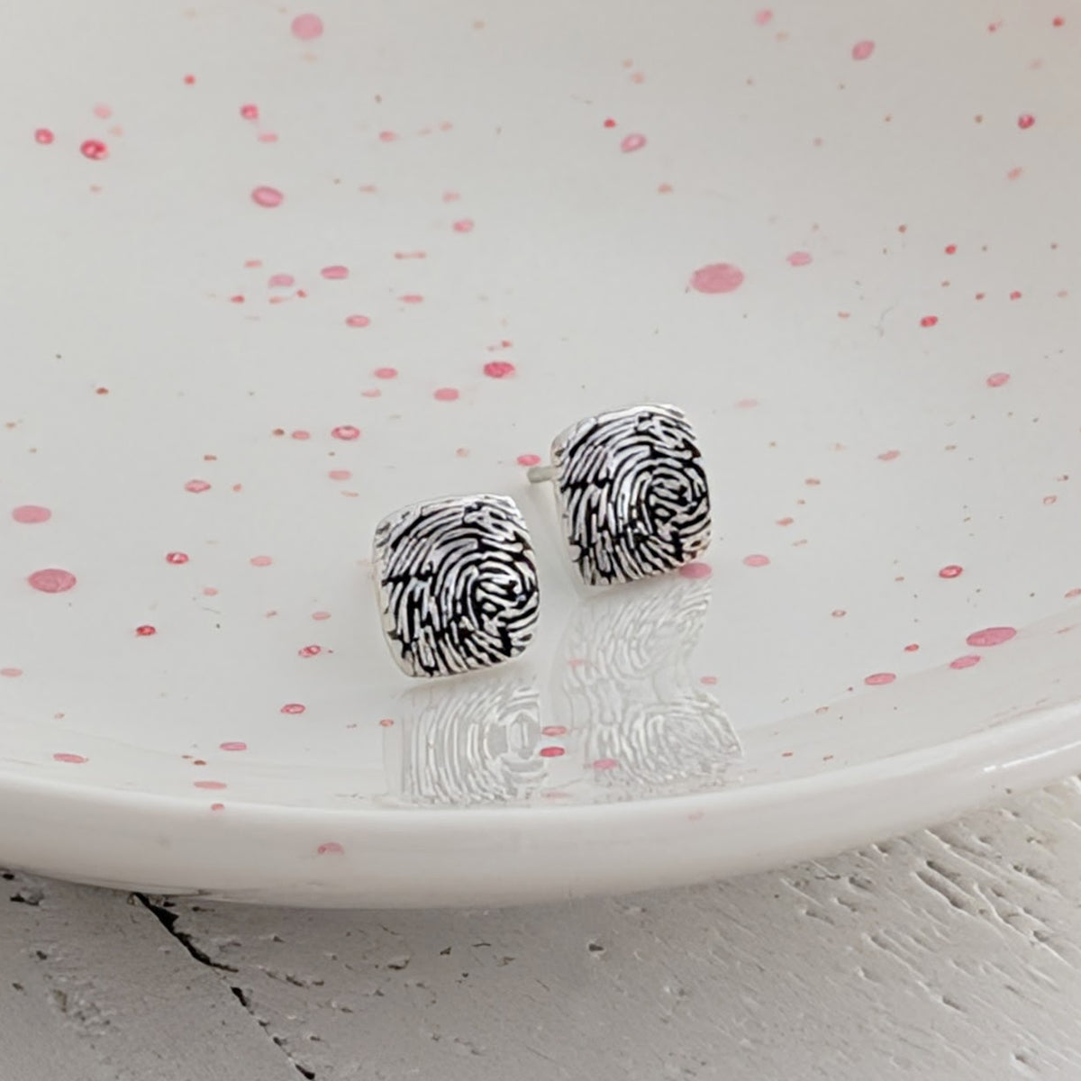 Handmade fingerprint stud earrings with softly rounded cushion-shaped faces, available in sterling silver and solid gold, personalised with your loved one's fingerprint.