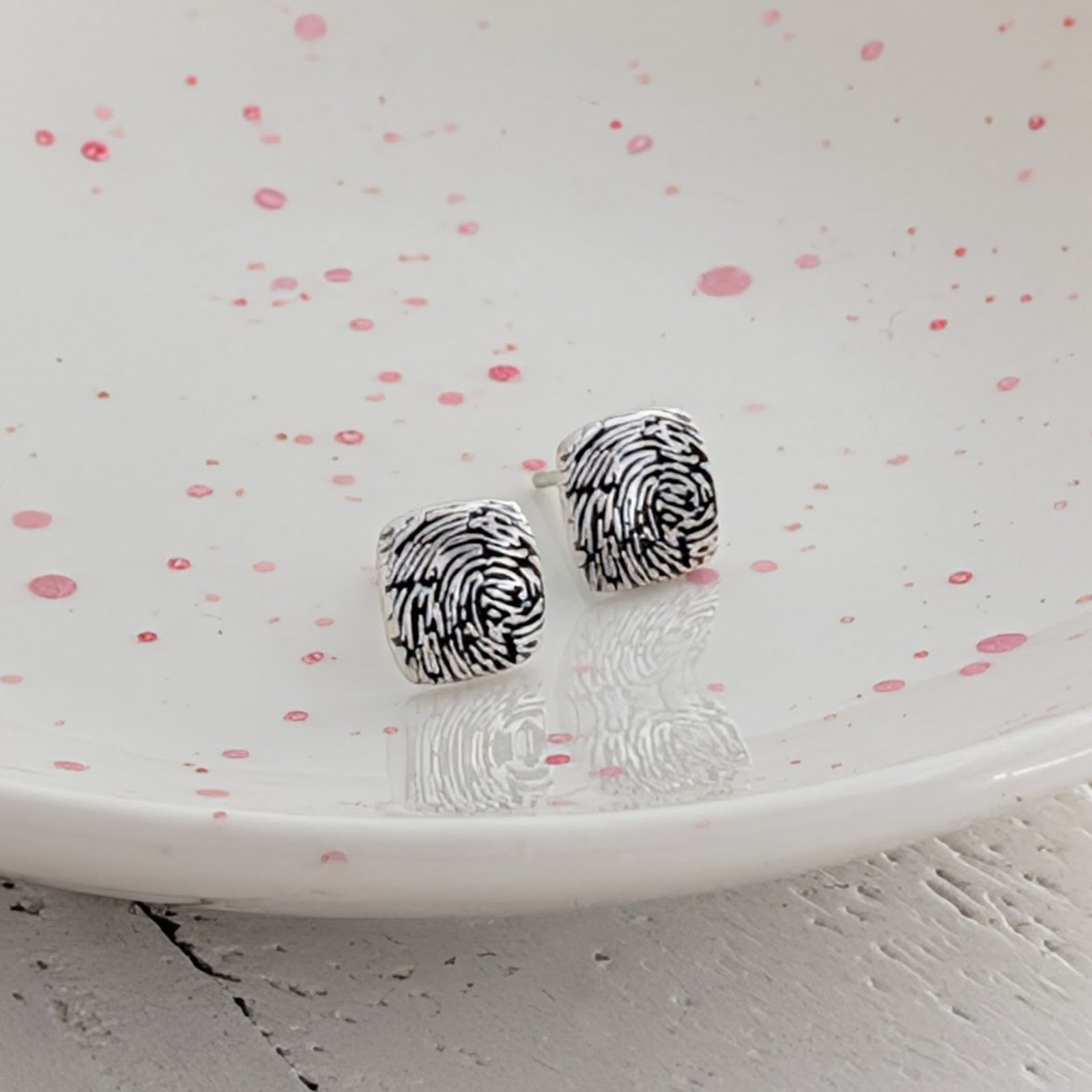Handmade fingerprint stud earrings with softly rounded cushion-shaped faces, available in sterling silver and solid gold, personalised with your loved one's fingerprint.