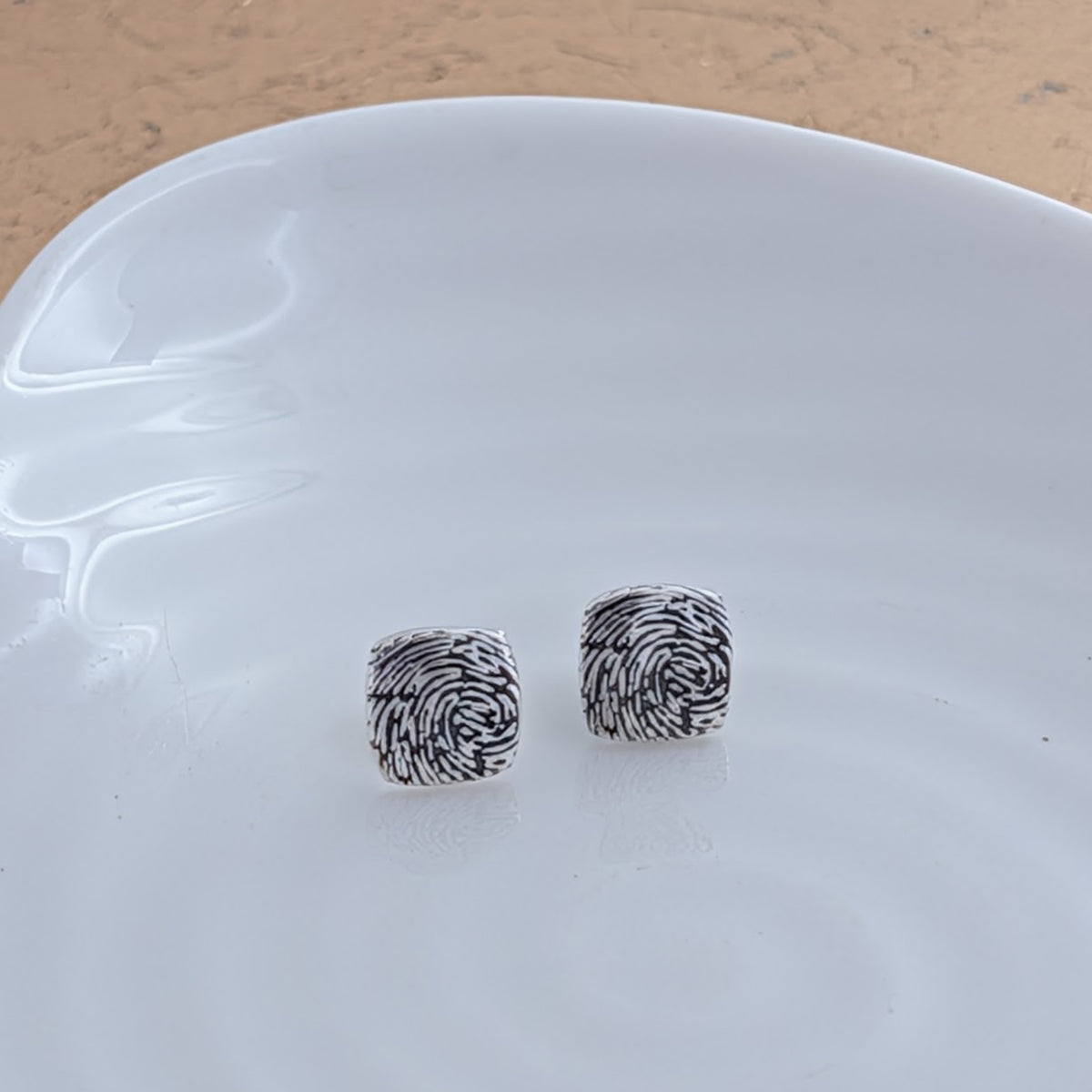 Bespoke fingerprint cushion earrings crafted in silver or gold, preserving the intricate ridges and whorls of a real fingerprint in a timeless everyday design.