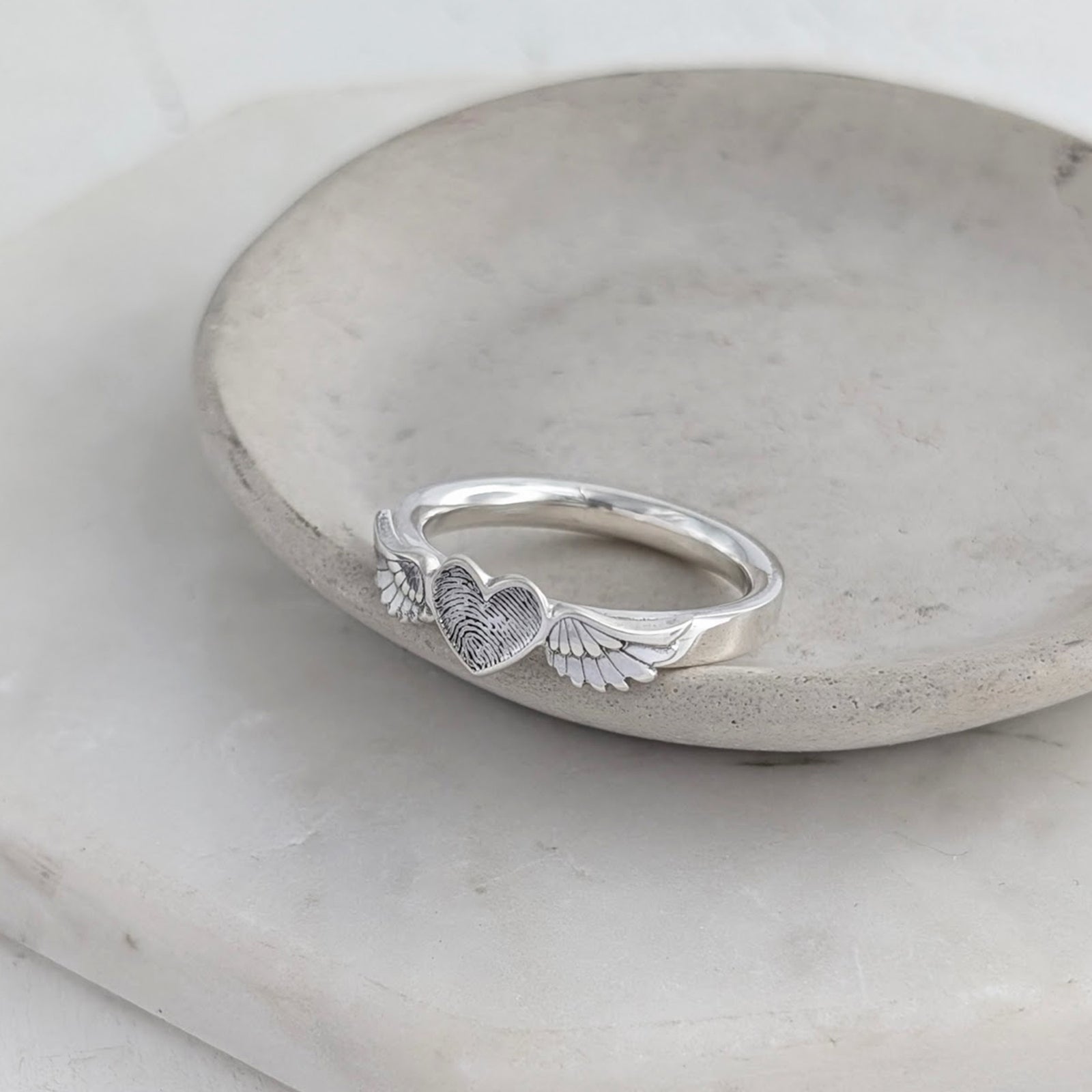 Handmade fingerprint heart and angel wings ring in sterling silver, personalised with a loved one’s fingerprint.