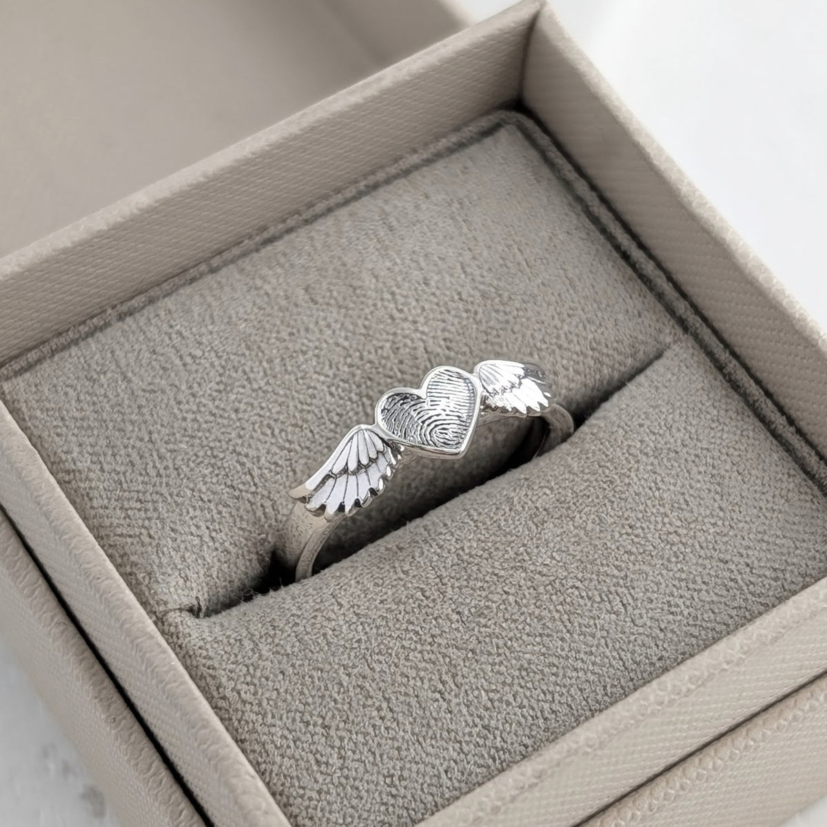 Fingerprint keepsake ring with heart and angel wings, handmade in sterling silver as personalised memorial jewellery.