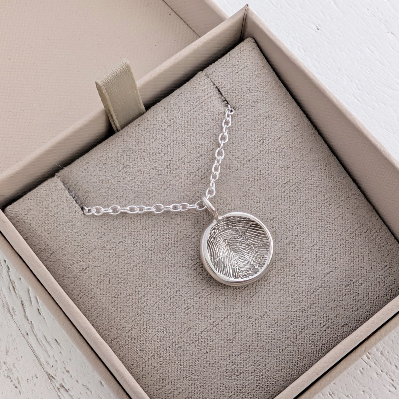 Handmade Circular Fingerprint Charm crafted from silver or gold and personalised with a genuine fingerprint. A meaningful memorial jewellery piece and thoughtful keepsake gift for family, friends or loved ones.