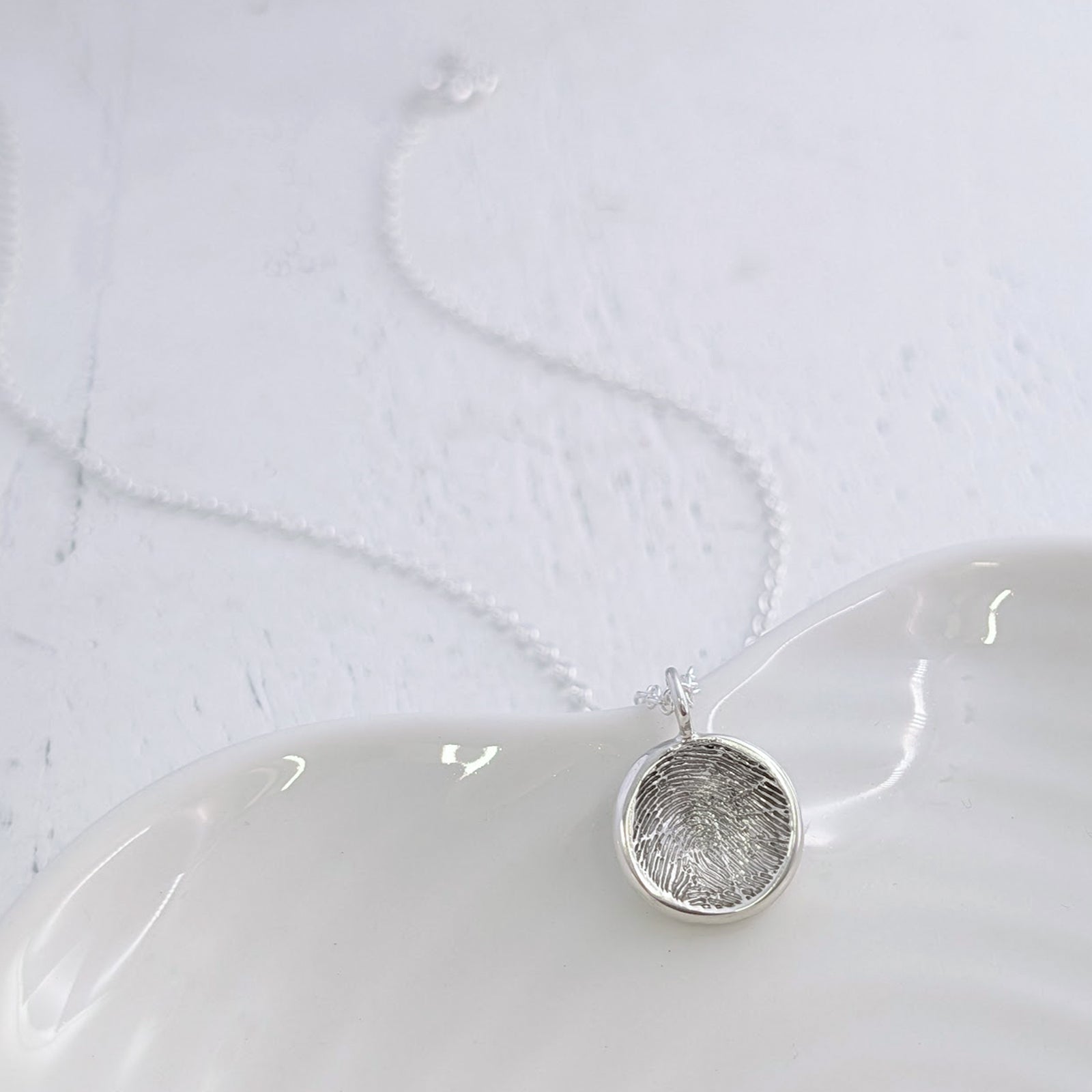 Personalised Soft Circle Fingerprint Charm available in sterling silver, 9ct gold or 18ct gold. Handmade to order and engraved with your loved one’s unique fingerprint, preserving precious memories in beautiful detail.