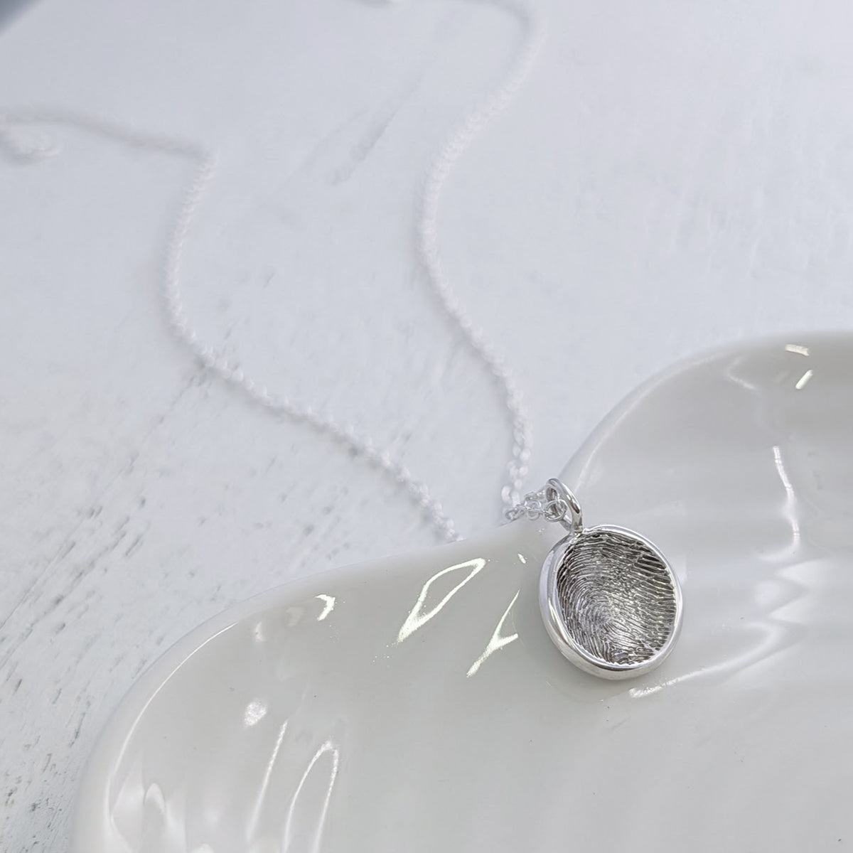 Bespoke Soft Circle Fingerprint Charm featuring your own fingerprint engraved into a contemporary round charm. Individually handcrafted in the UK from sterling silver or solid gold for a truly personal piece of jewellery.