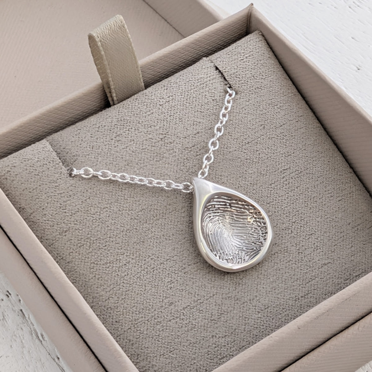 Organic Droplet Fingerprint Charm personalised with a real fingerprint and handcrafted in the UK. A meaningful keepsake charm and memorial jewellery piece available in sterling silver and solid gold.