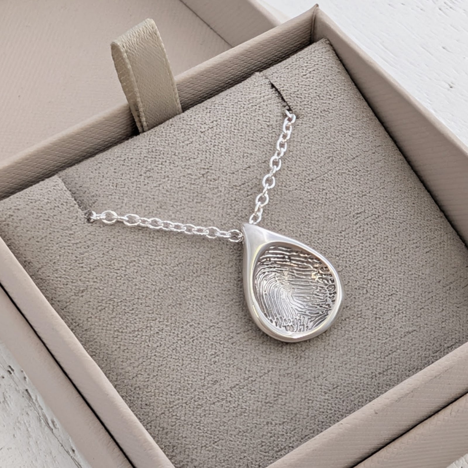 Organic Droplet Fingerprint Charm personalised with a real fingerprint and handcrafted in the UK. A meaningful keepsake charm and memorial jewellery piece available in sterling silver and solid gold.