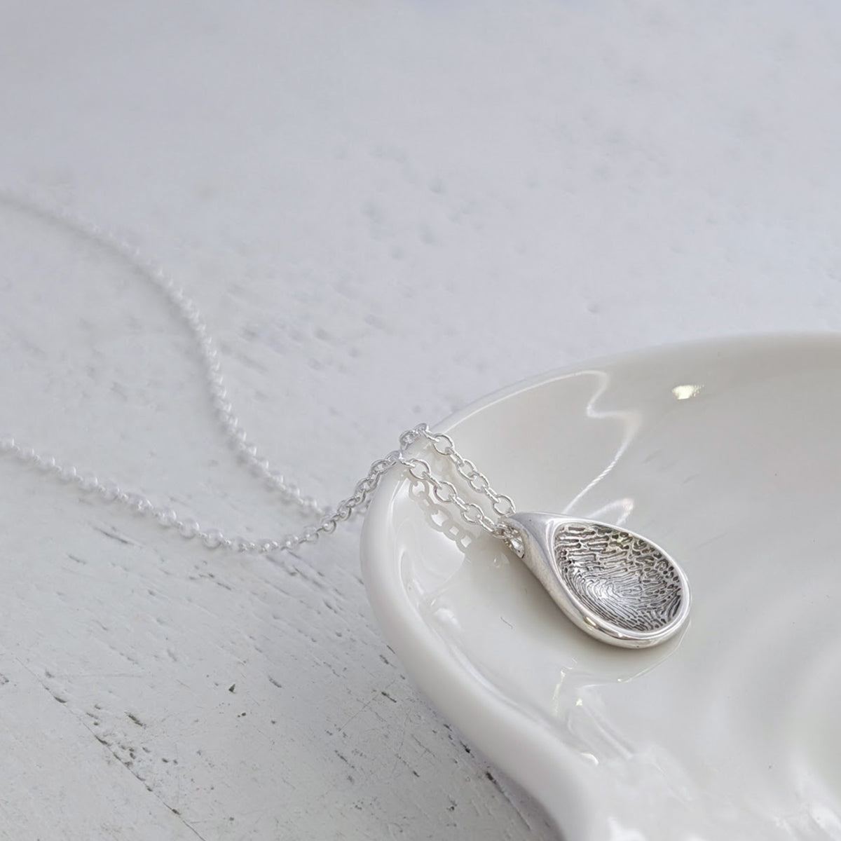 Bespoke Soft Droplet Fingerprint Charm crafted from sterling silver or solid gold. This elegant personalised fingerprint jewellery captures every loop and whorl, creating a lasting connection to someone special.
