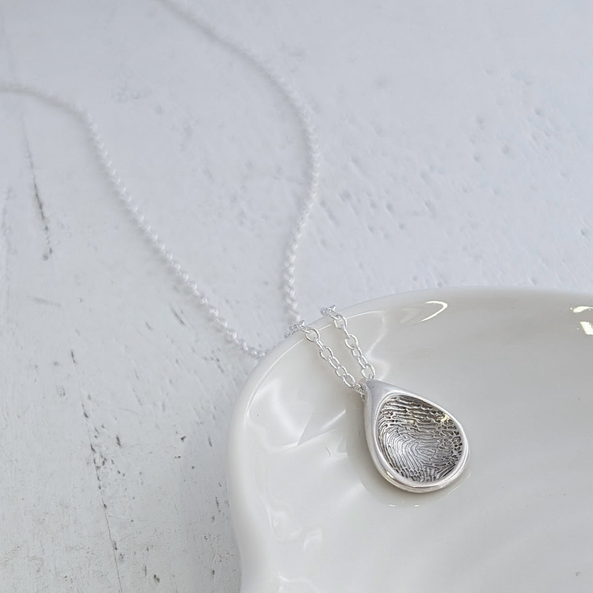 Handmade Droplet Fingerprint Charm featuring your loved one’s unique fingerprint engraved into a contemporary teardrop-inspired design. Available in silver or gold as a timeless memorial jewellery keepsake.