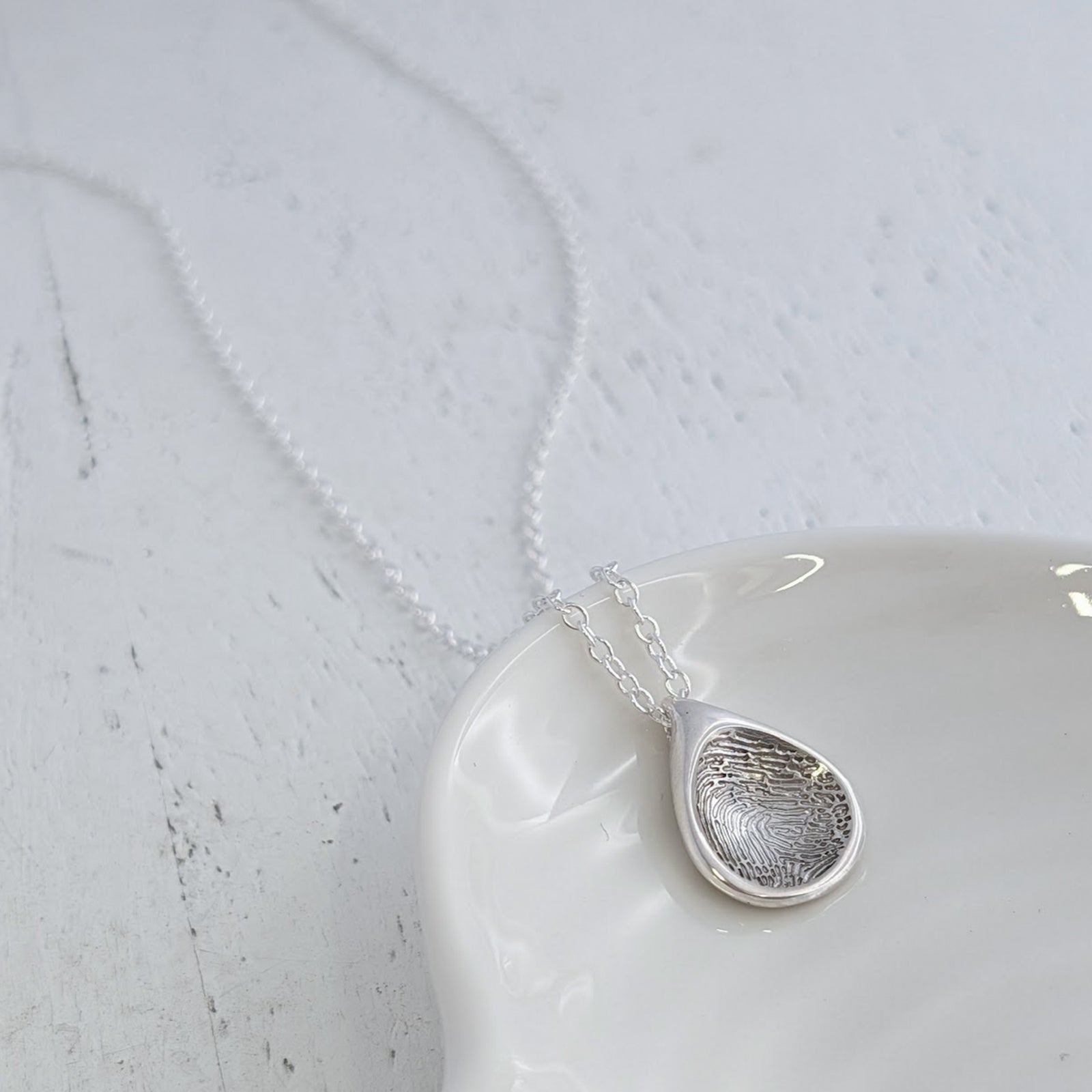 Handmade Droplet Fingerprint Charm featuring your loved one’s unique fingerprint engraved into a contemporary teardrop-inspired design. Available in silver or gold as a timeless memorial jewellery keepsake.