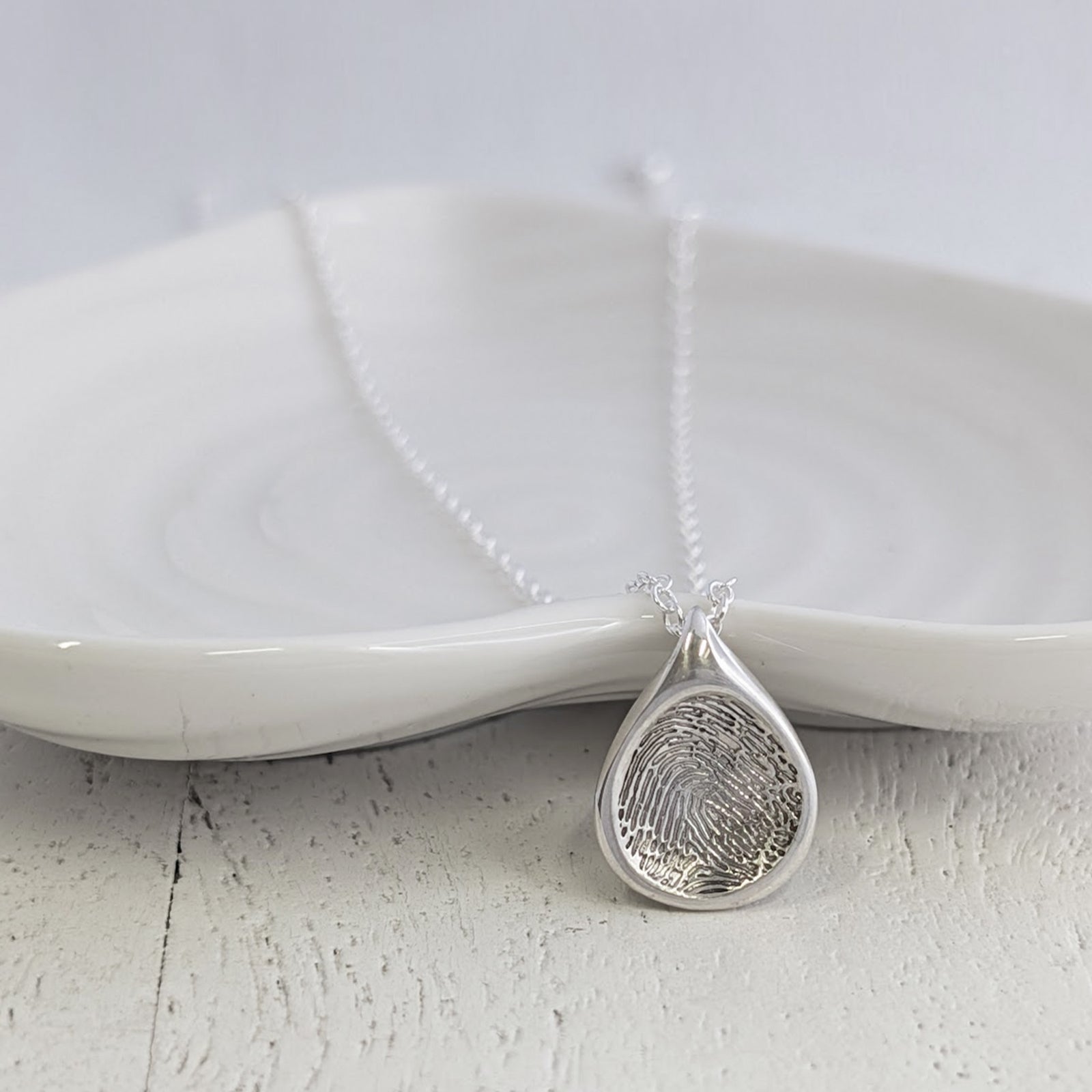 Personalised Soft Droplet Fingerprint Charm available in sterling silver, 9ct gold or 18ct gold. Handmade to order and engraved with a genuine fingerprint, preserving precious memories in beautiful detail.