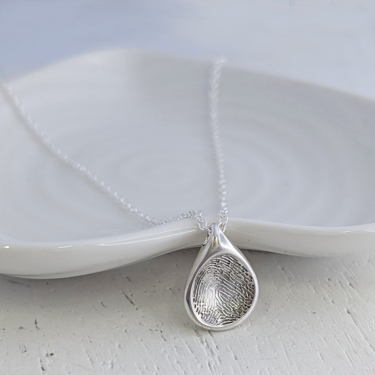 Soft Droplet Fingerprint Charm handcrafted in sterling silver or solid gold. Personalised with a real fingerprint and designed in a smooth organic droplet shape, creating a meaningful keepsake jewellery gift.
