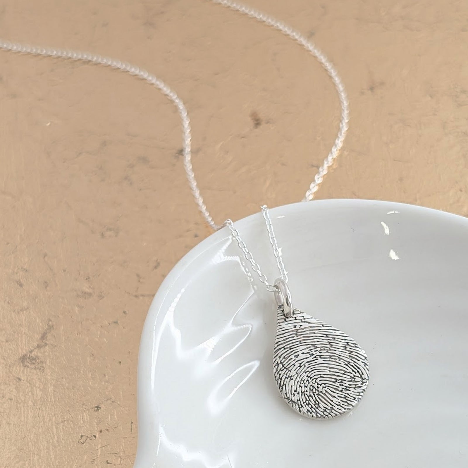 Fingerprint Droplet Necklace in Silver or Gold – Elegant droplet-shaped pendant engraved with a real fingerprint. Handmade in sterling silver or solid gold, creating a meaningful keepsake or memorial necklace.