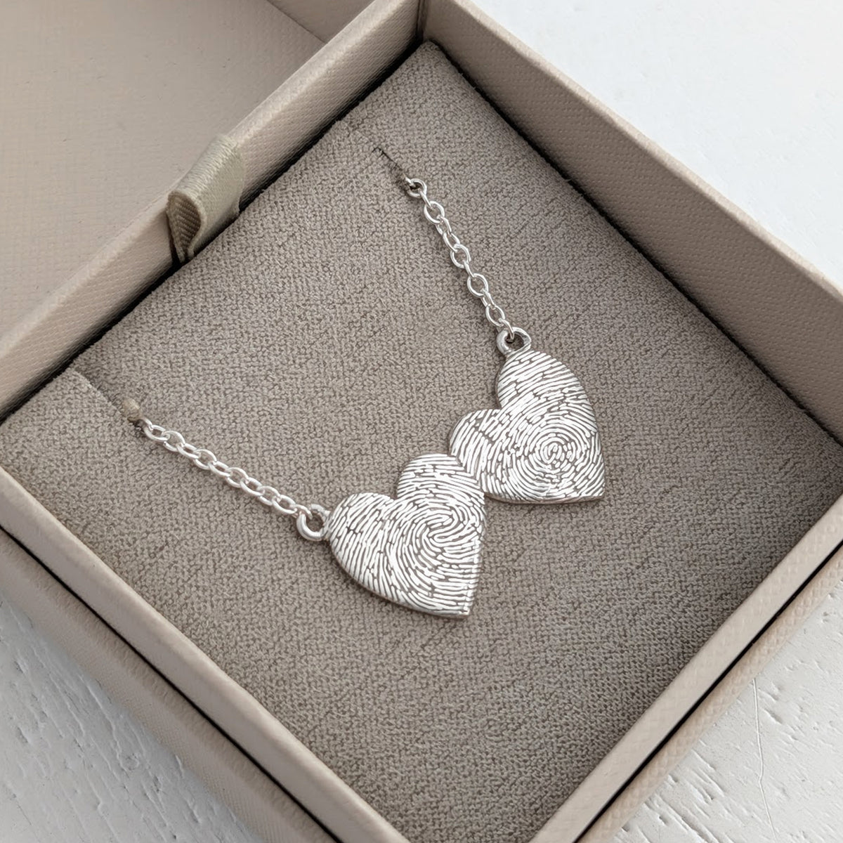 Personalised Double Heart Fingerprint Necklace – Elegant heart-to-heart necklace featuring two fingerprint engraved hearts suspended from a delicate chain. A meaningful keepsake gift for couples, parents, or family members.