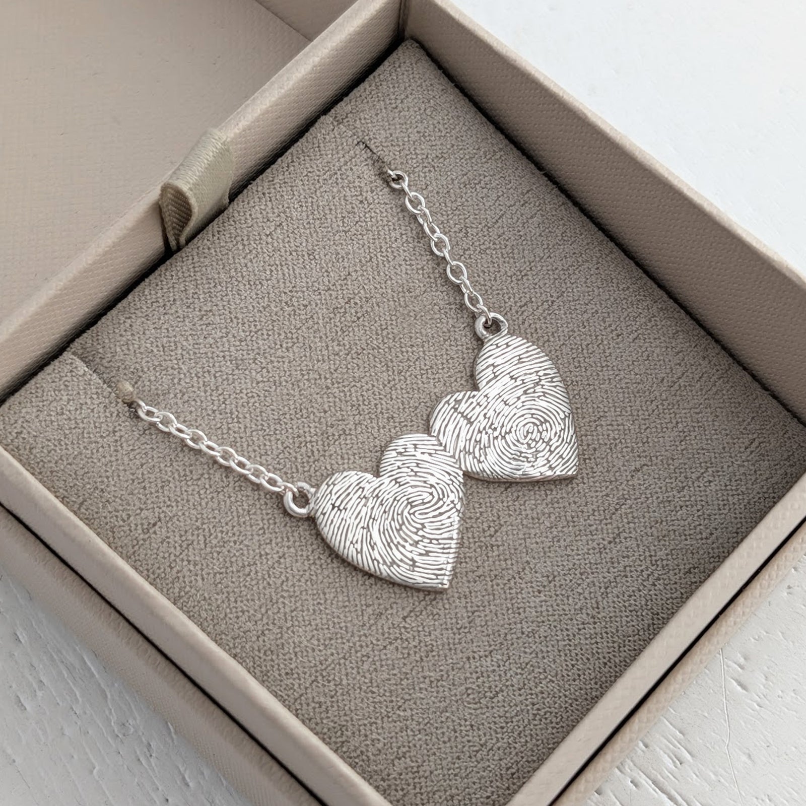 Personalised Double Heart Fingerprint Necklace – Elegant heart-to-heart necklace featuring two fingerprint engraved hearts suspended from a delicate chain. A meaningful keepsake gift for couples, parents, or family members.