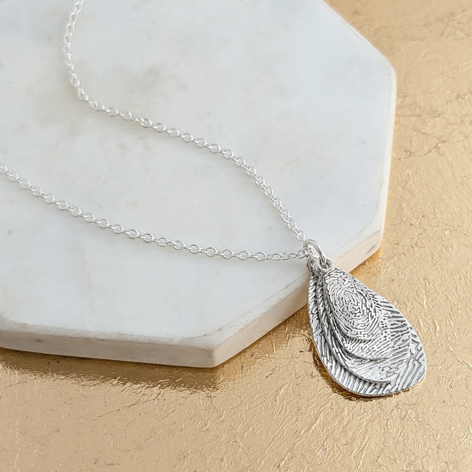 Organic Fingerprint Droplet Necklace in Silver or Gold – A beautifully flowing stack of organic droplet pendants engraved with a real fingerprint. Handmade in sterling silver or solid gold, creating a unique and meaningful keepsake necklace.