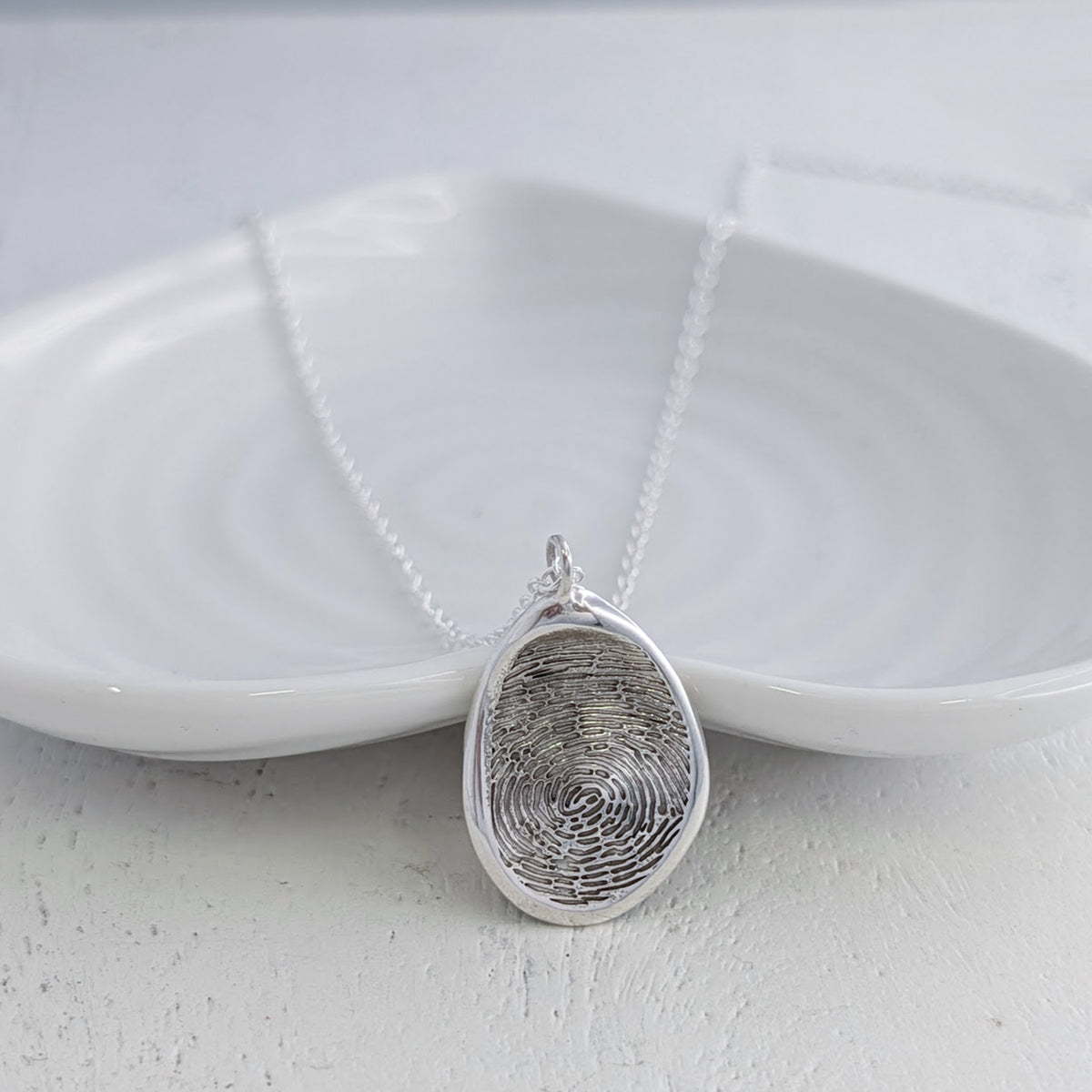 Organic Fingerprint Pendant Necklace handcrafted in sterling silver or solid gold. Featuring your loved one’s real fingerprint engraved within a softly sculpted organic shape, creating a meaningful keepsake jewellery gift or memorial necklace.