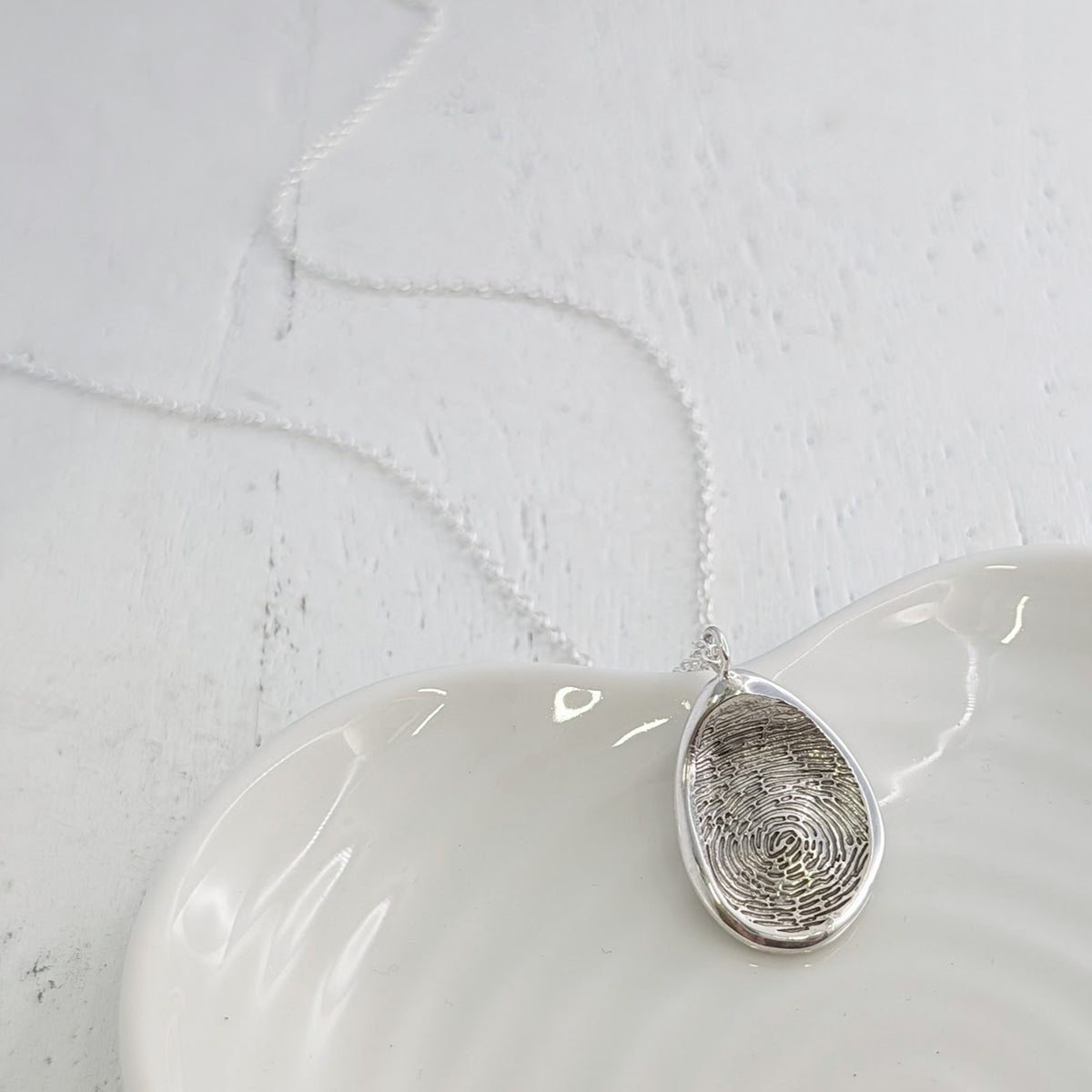 Personalised Organic Fingerprint Necklace available in sterling silver, 9ct gold or 18ct gold. Handmade to order and engraved with a genuine fingerprint, this contemporary pendant captures every unique detail in a timeless design.