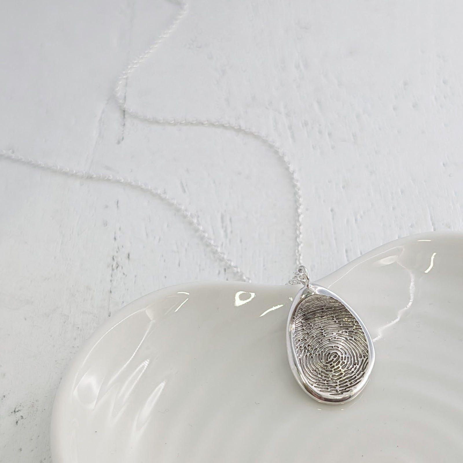 Personalised Organic Fingerprint Necklace available in sterling silver, 9ct gold or 18ct gold. Handmade to order and engraved with a genuine fingerprint, this contemporary pendant captures every unique detail in a timeless design.