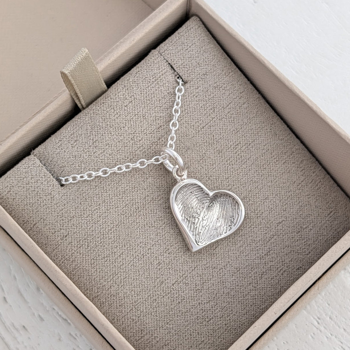 Bespoke Soft Heart Fingerprint Charm featuring a real fingerprint engraved within a contemporary heart design. Individually handcrafted in the UK from sterling silver or solid gold, creating a truly personal piece of fingerprint jewellery.