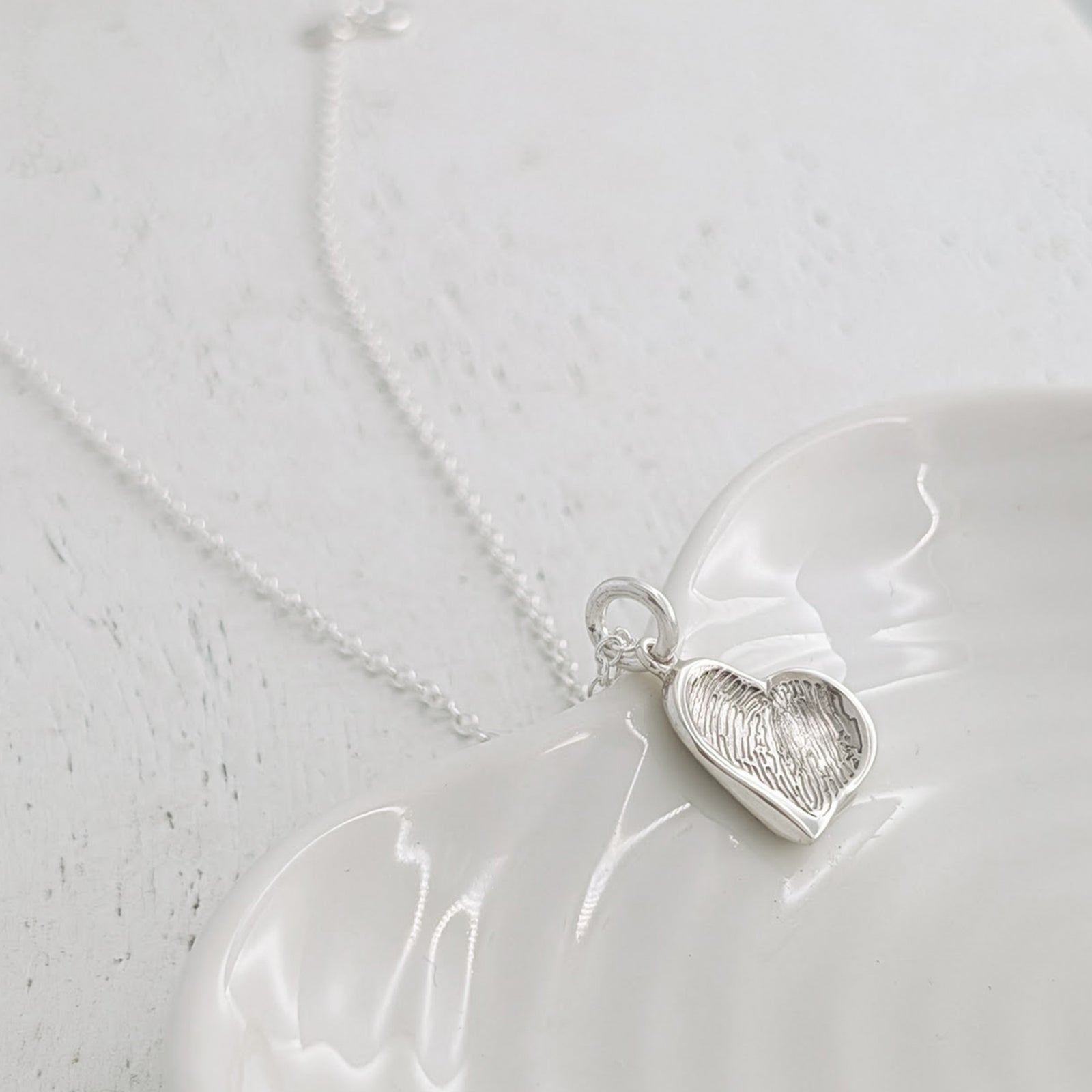 Handmade Heart Fingerprint Charm crafted from silver or gold and personalised with your loved one’s fingerprint. A beautiful memorial jewellery piece and sentimental keepsake designed to be treasured for years to come.