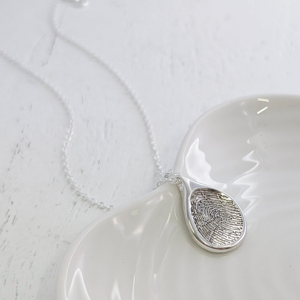 Bespoke Droplet Fingerprint Pendant Necklace featuring your own fingerprint engraved into a smooth teardrop shape. Available in sterling silver and solid gold, this elegant fingerprint jewellery is handmade in the UK.