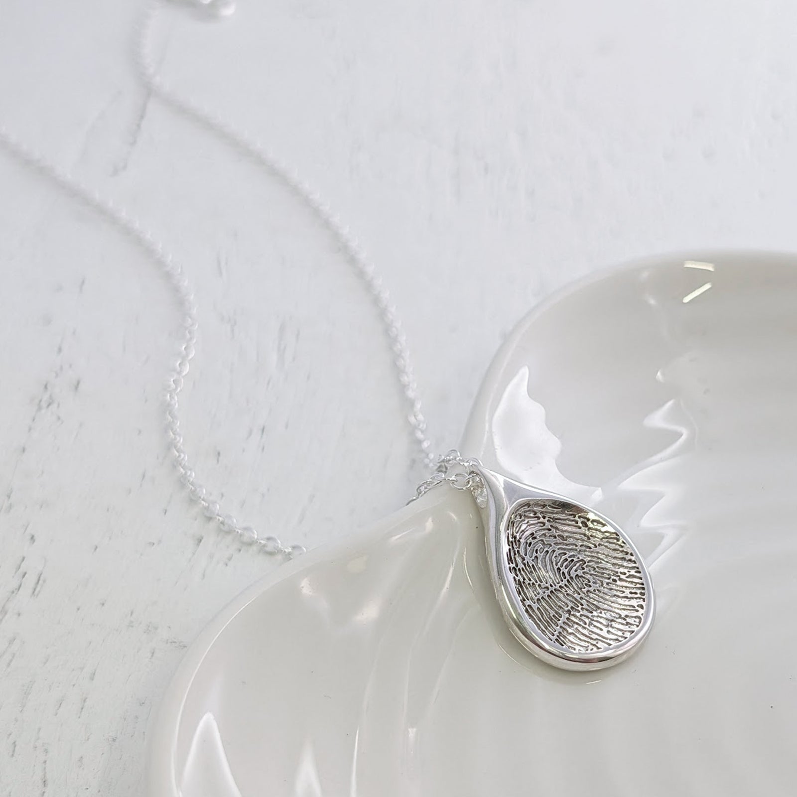 Bespoke Droplet Fingerprint Pendant Necklace featuring your own fingerprint engraved into a smooth teardrop shape. Available in sterling silver and solid gold, this elegant fingerprint jewellery is handmade in the UK.