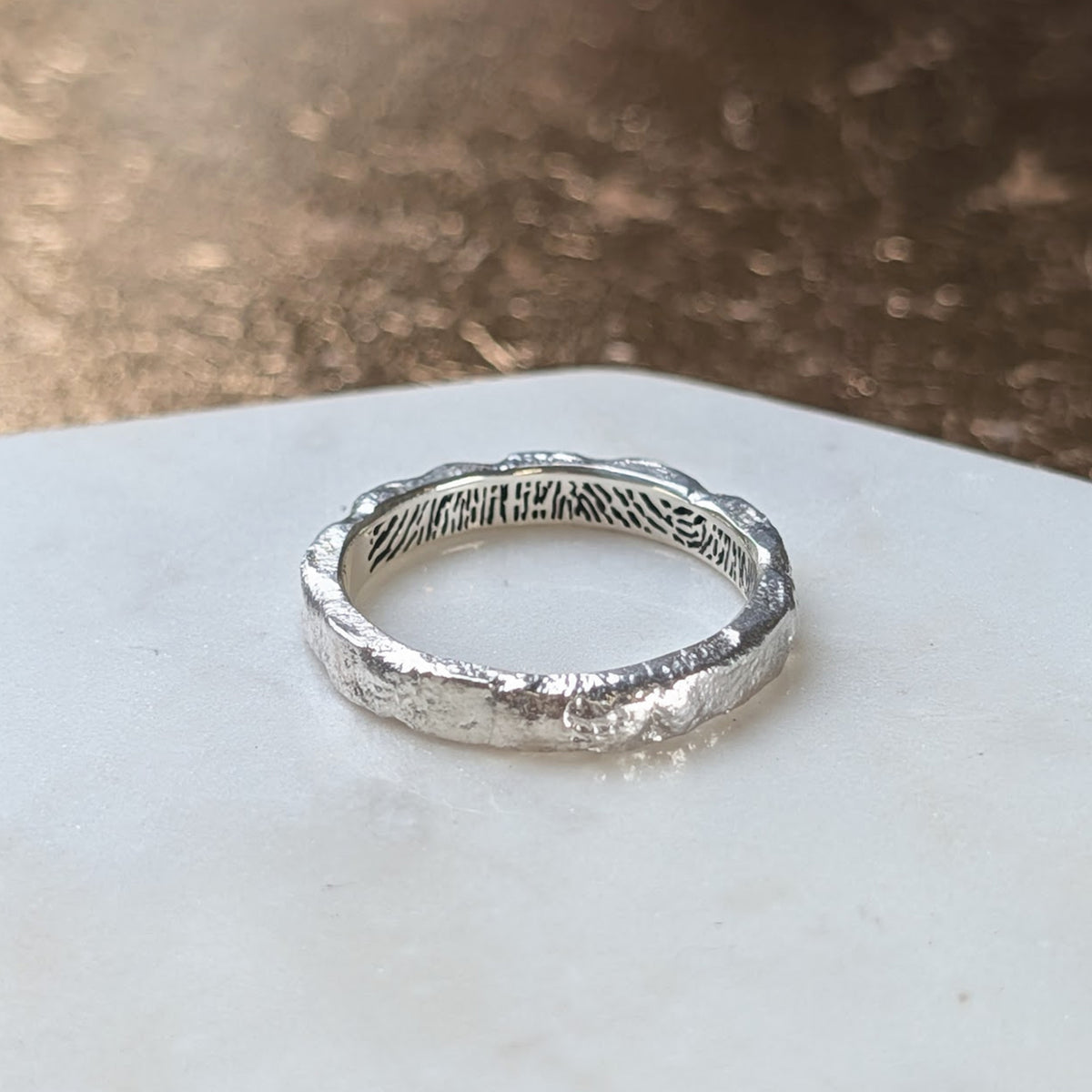 Handmade molten sterling silver fingerprint ring featuring a unique organic texture and a personalised fingerprint engraved inside the band.