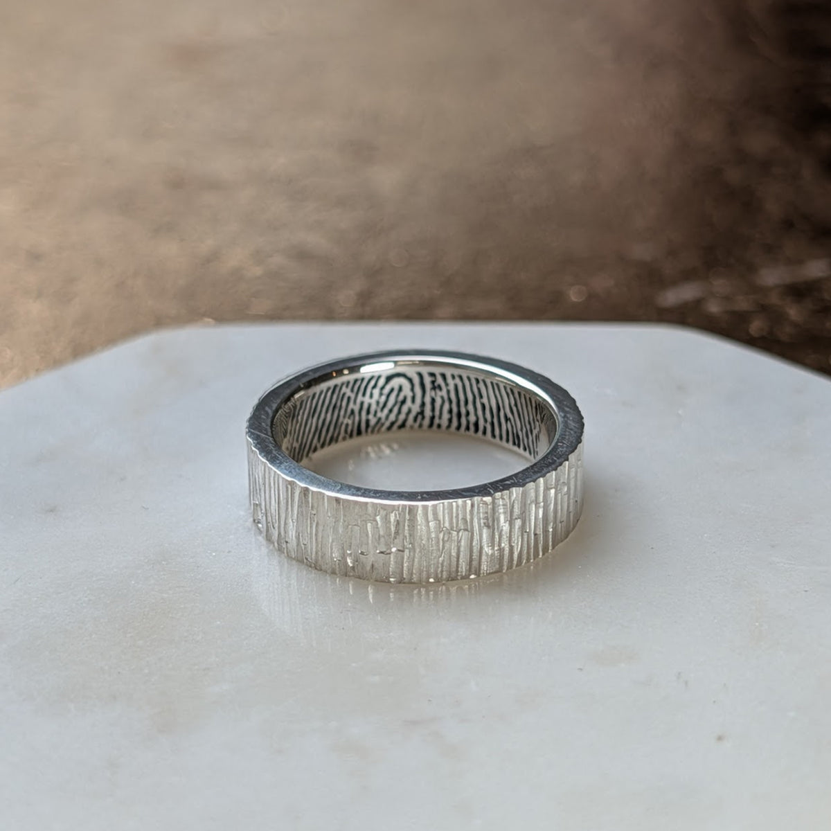 Handmade wide bark texture fingerprint ring in sterling silver, featuring a personalised fingerprint engraved around the inside of the band.
