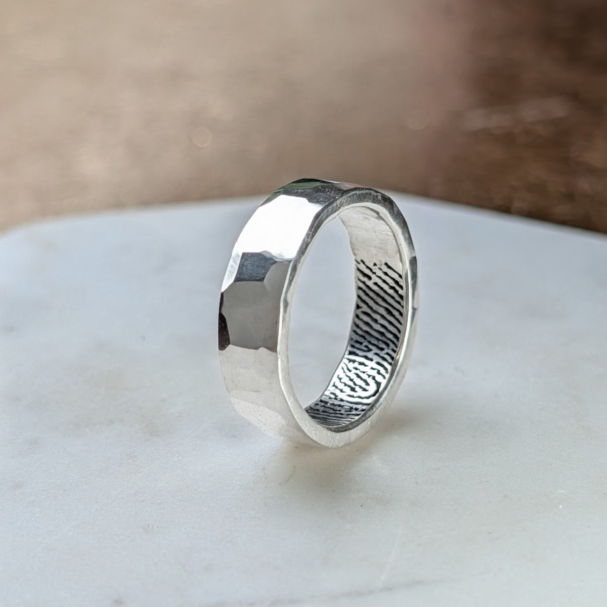 Handmade wide hammered sterling silver fingerprint ring, featuring a faceted finish and a personalised fingerprint engraved inside the band.