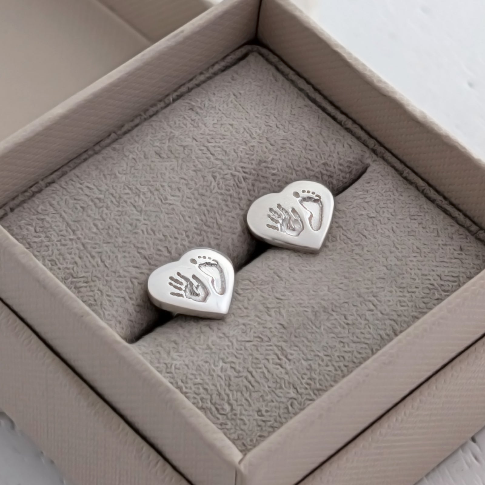 Sterling silver heart stud earrings engraved with your child's handprint and footprint. Handmade keepsake jewellery capturing precious memories of your baby in beautiful detail.