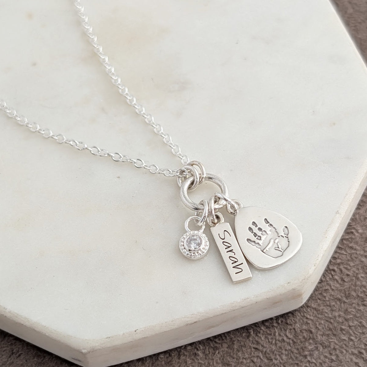 Personalised droplet silver necklace engraved with child's own handprint or footprint and birthstone.
