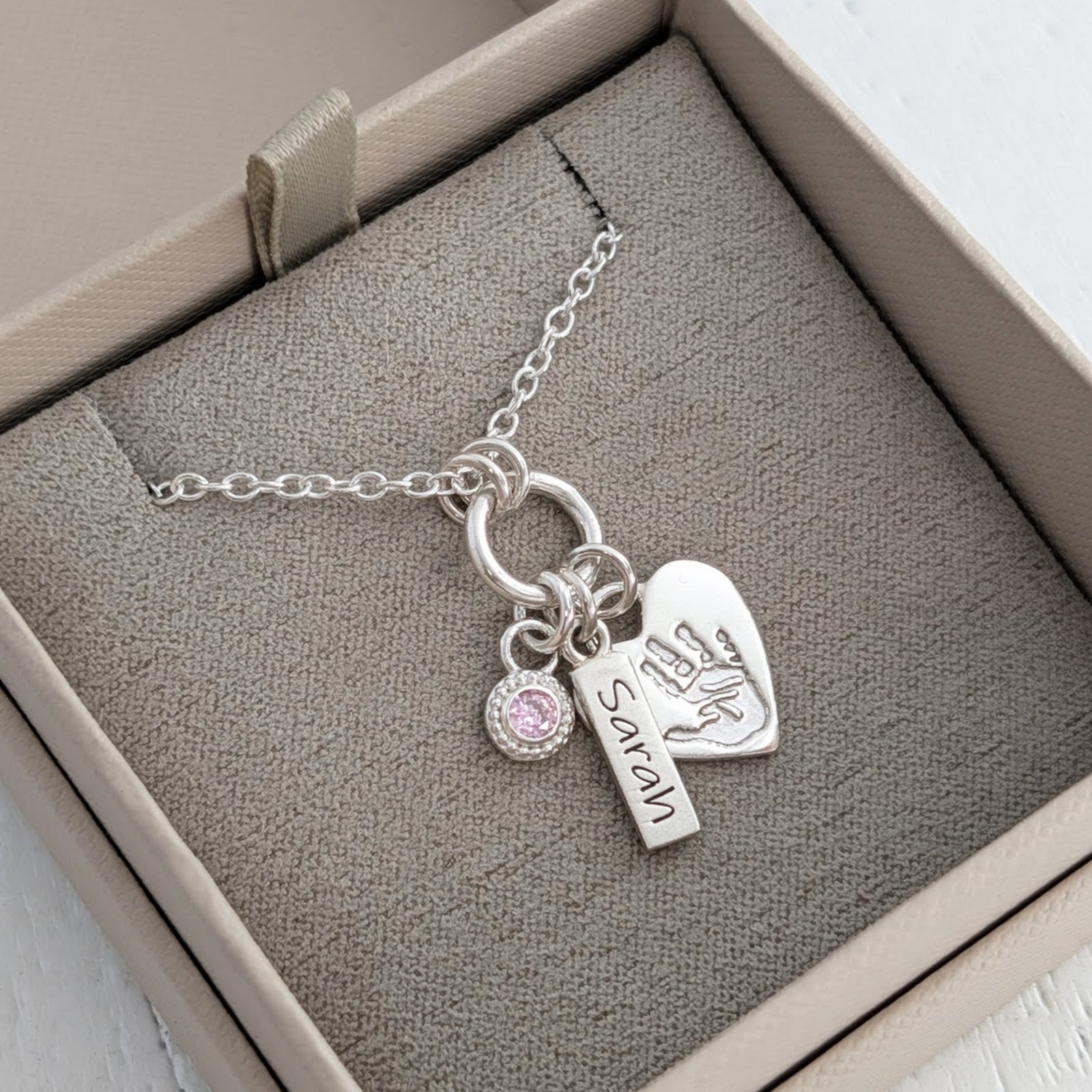 Love inspired silver necklace engraved with child's own handprint or footprint and birthstone.