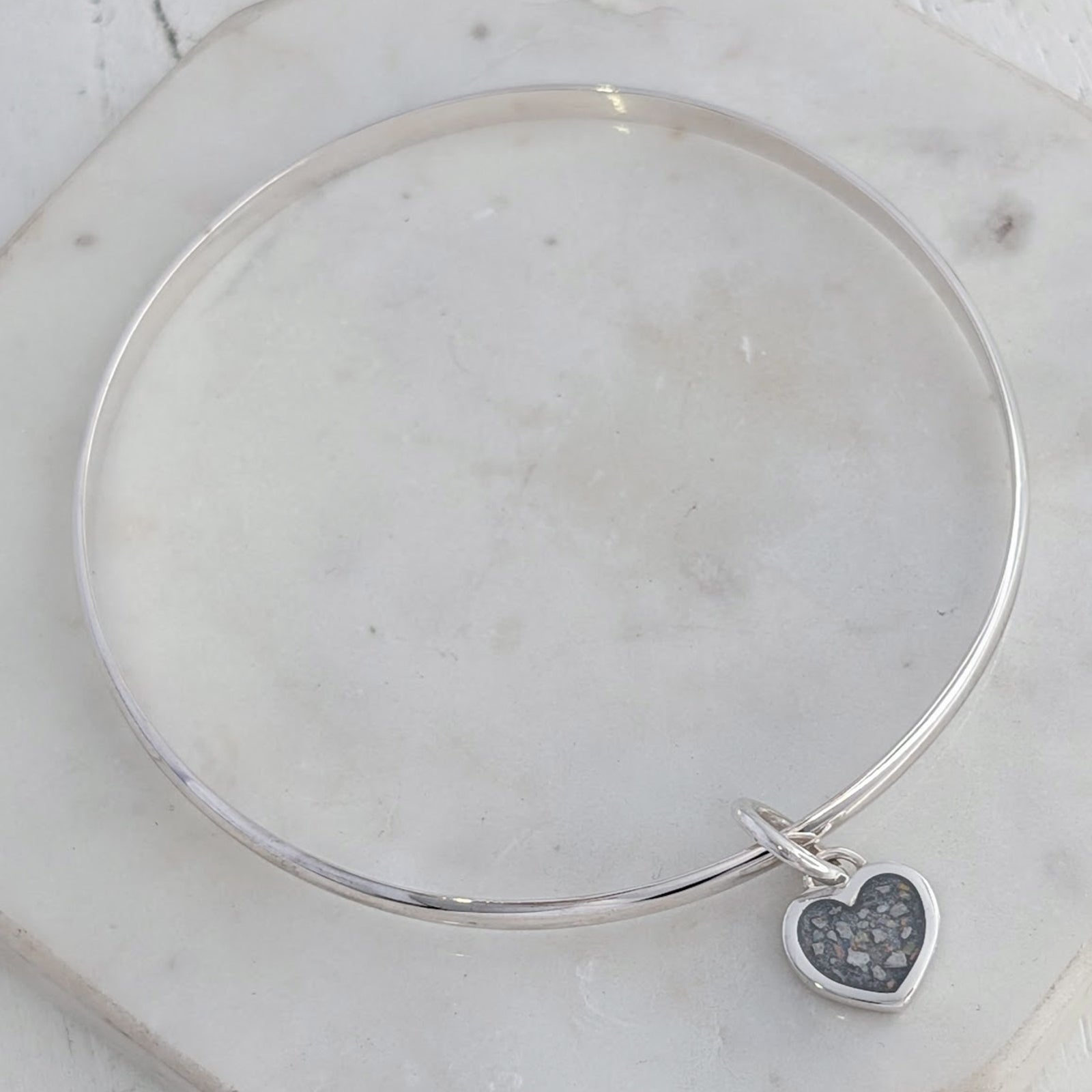Memorial ashes heart charm bangle handcrafted in sterling silver, featuring a delicate heart charm filled with cremation ashes and opal inclusions, creating a meaningful remembrance jewellery piece.