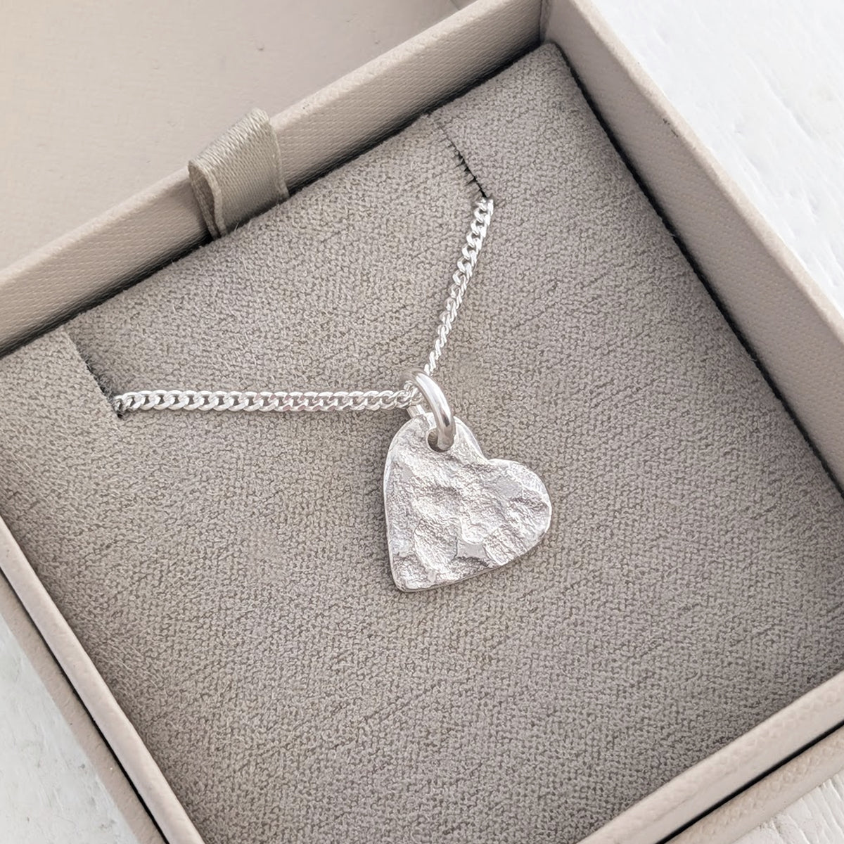 Personalised memorial ashes necklace with organic heart charm, handcrafted in Shropshire and bearing the unique impression of cremation ashes within its textured surface.