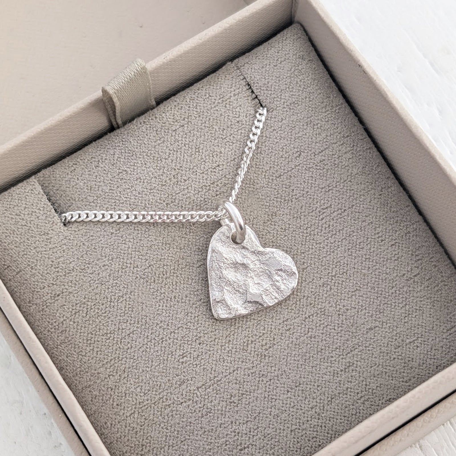 Personalised memorial ashes necklace with organic heart charm, handcrafted in Shropshire and bearing the unique impression of cremation ashes within its textured surface.