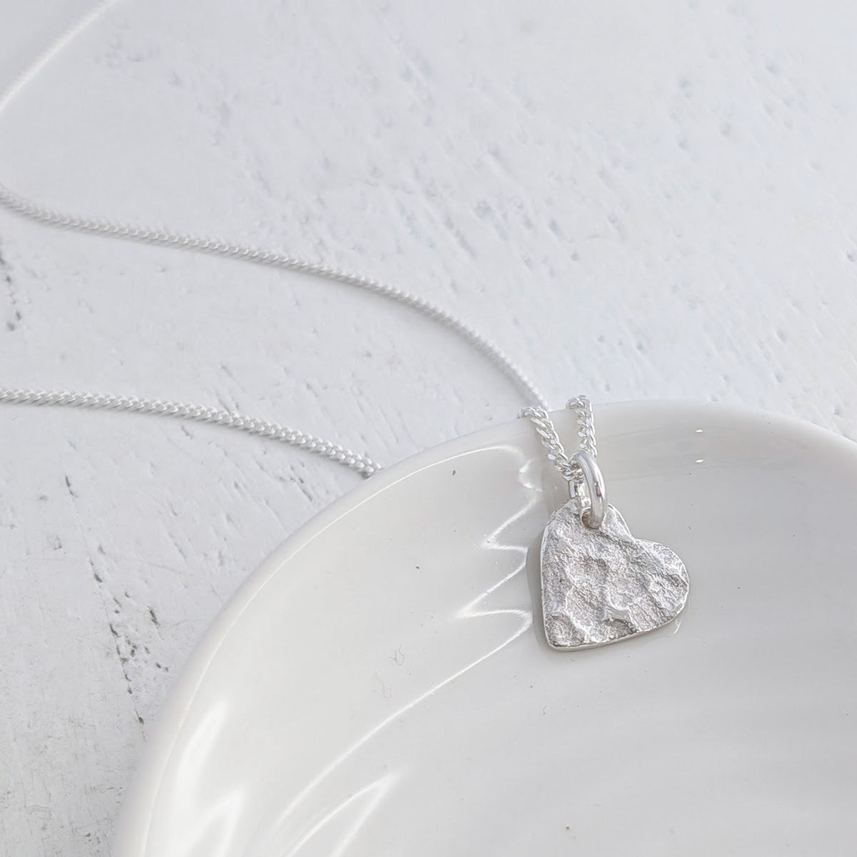 Handmade ashes imprint heart pendant in sterling silver, featuring a unique surface texture formed using cremation ashes and suspended from a silver chain.
