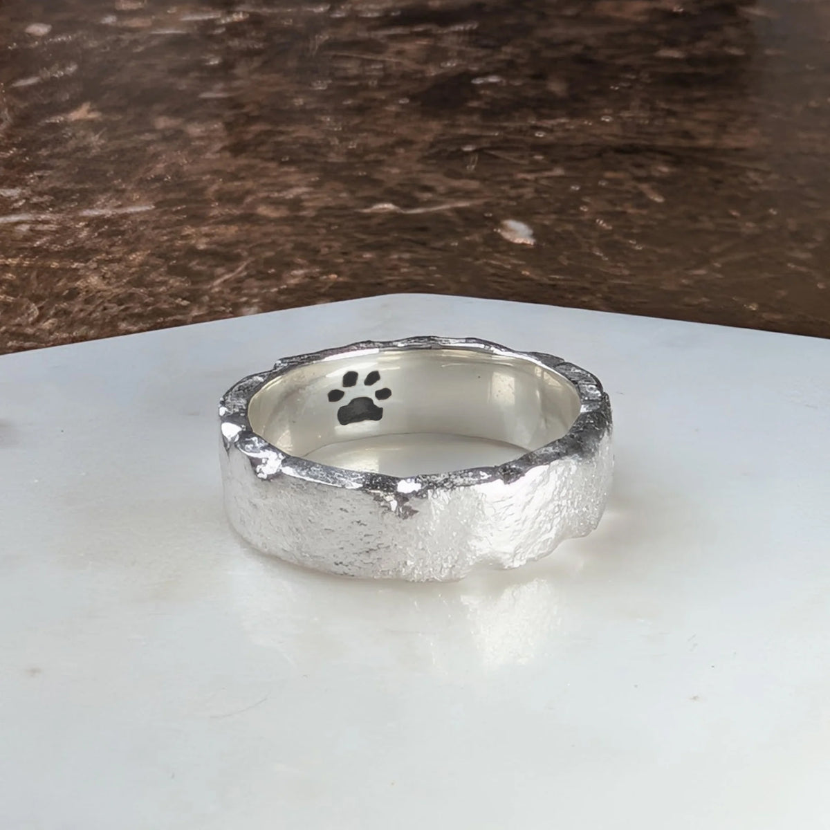 Handmade molten sterling silver paw print ring, personalised pet memorial jewellery featuring an engraved pawprint inside a unique organic band.