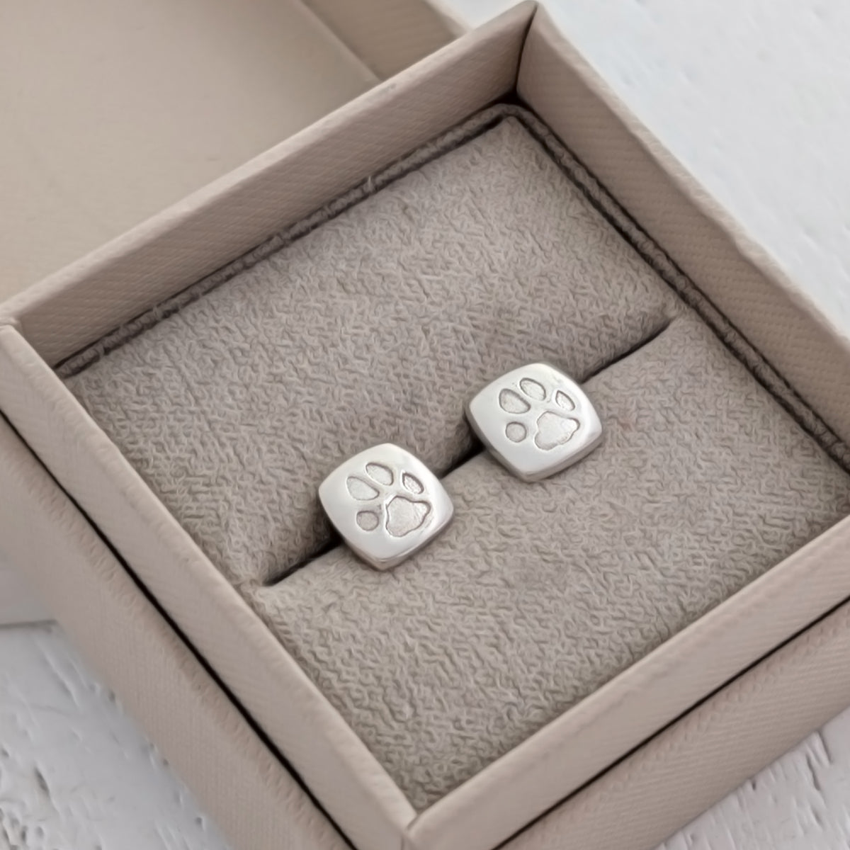 Handmade sterling silver cushion pawprint earrings engraved with your pet's own paw print. Meaningful pet memorial earrings and keepsake jewellery for animal lovers and pet loss gifts.