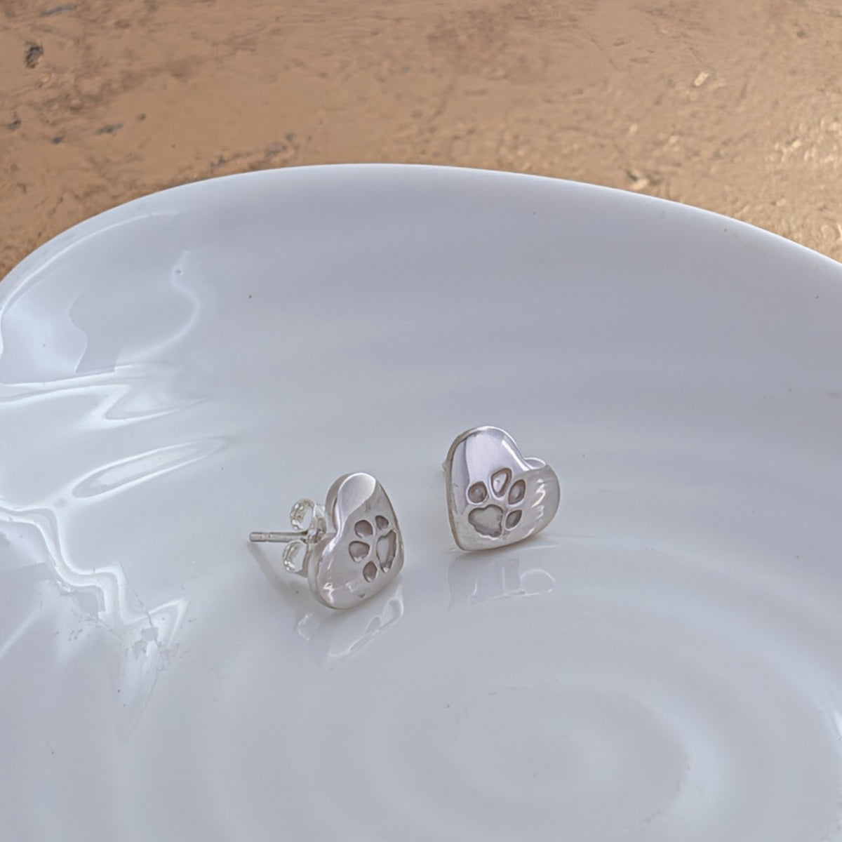 Personalised pawprint stud earrings featuring real pet paw prints engraved onto heart-shaped sterling silver studs. Handmade pet remembrance jewellery crafted in Shropshire.