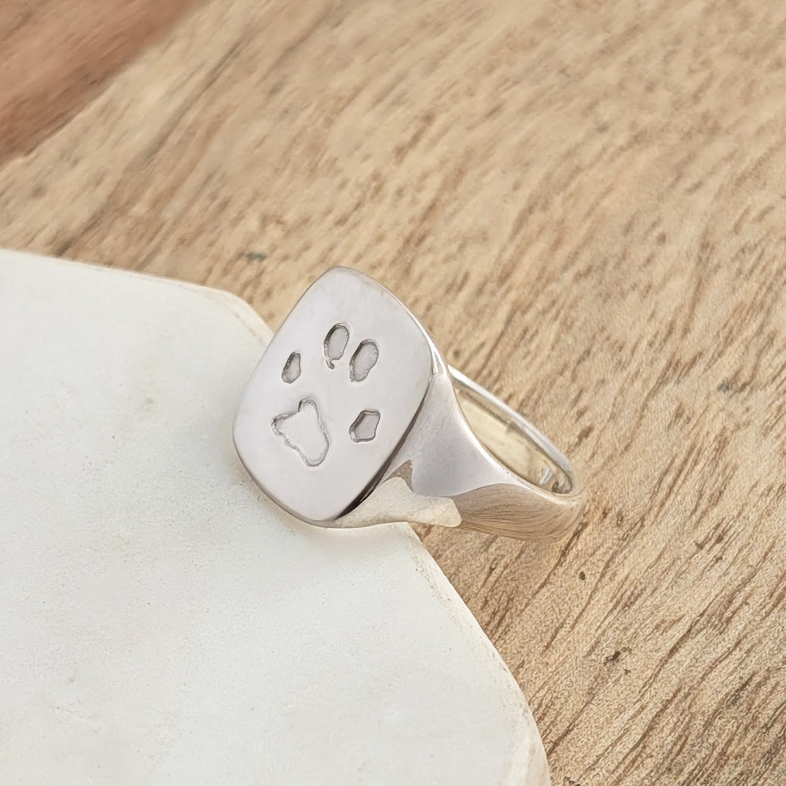 Handmade silver pawprint signet ring for pet lovers, personalised memorial jewellery crafted from sterling silver with a detailed paw print design.